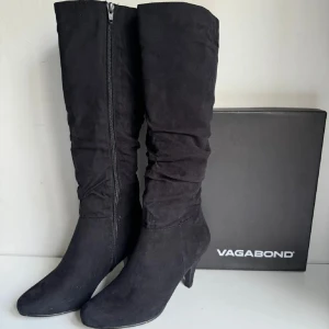 Svarta stövlar från Vagabond - Snygga svarta stövlar från Vagabond med dragkedja på sidan. Tillverkade i mocka med en elegant klack och spetsig tå. Perfekta för en stilren look.