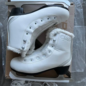 Vita skridskor från Spin - Snygga vita skridskor från Spin med pälsdetaljer runt kanten. De har en klassisk design med snörning och svart sula. Perfekta för vinterns isäventyr.