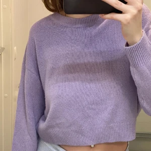 Lila stickad tröja - Säljer en söt lila stickad tröja med en croppad design. Tröjan har långa ärmar och en rund halsringning, perfekt för en avslappnad stil. Passar bra till jeans eller kjol för en trendig look. 💜