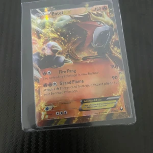 Pokémonkort Entei EX - Säljer ett Pokémonkort med Entei EX. Kortet har en glansig yta och visar Entei i en kraftfull pose. Det har attacker som Fire Fang och Grand Flame. Kortet är numrerat 13/108 och är i en skyddande plastficka.