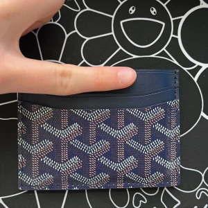 Kortplånbok - Snygg och kompakt kortplånbok med ett unikt mönster i blått och vitt. Perfekt för att hålla dina kort organiserade. Den har flera kortfack och en stilren design.