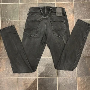 Mörkgrå jeans från Replay - Snygga svarta jeansbyxor från Replay i modellen Anbass. De har en klassisk femficksdesign med knapp och dragkedja framtill. Jeansen har en diskret Replay-logga i blått vid fickan och är perfekta för en stilren look. Vi snabb affär går ner i pris 