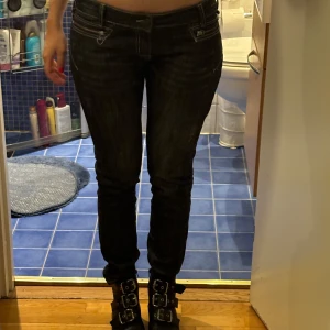Svarta jeans med dragkedja - Snygga svarta jeans med tight passform och låg midja. De har coola dragkedjor framtill och klassiska bakfickor. Perfekta för en stilren look.