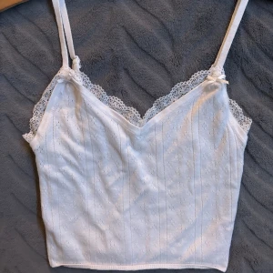 Vit linne med spetsdetaljer - Ett gulligt vitt linne med jätte fina detaljer. Säljer då jag tycker det är nån cm för kort. Banden är ställbara. 🤍