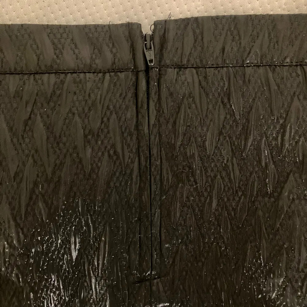 Snygg svart kjol med textur och två dekorativa dragkedjor framtill. Kjolen har en dragkedja bak för enkel påklädning. Perfekt för en stilren look. Midjemått: 40cm, längd: 39cm💗. Hameet.