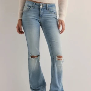 Ljusblå bootcut jeans med slitningar - Snygga ljusblå bootcut jeans med slitningar vid knäna. Knappt använda. Nypris 700 från Nelly