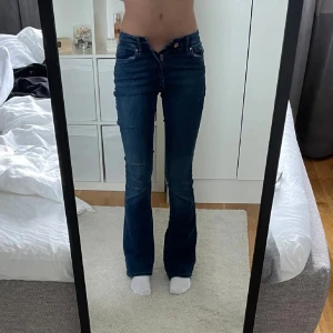 Blå bootcut jeans - Snygga blå bootcut jeans med låg midja och klassisk femficksdesign. Perfekta för en avslappnad stil med en touch av retro. Passar bra till både sneakers och klackar.