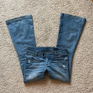 Lågmidjade bootcut jeans - Snygga blå bootcut jeans med låg midja och klassisk femficksdesign. Jeansen har en lätt slitning på framsidan och är perfekta för en avslappnad stil. Midjemått rakt över: 37 cm. Innerbenslängd: 75 cm. Benbredd: 27 cm💖💖