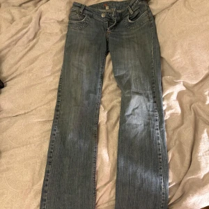 Blå jeans med broderad detalj - Snygga lågmidhade blå jeans med en broderad detalj på bakfickan. De har en klassisk femficksdesign och en bekväm passform. Perfekta för en avslappnad stil.