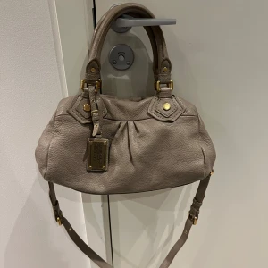  Marc Jacobs väska - Säljer en snygg grå handväska från Marc Jacobs i skinn. Väskan är nästintill helt ny. Skriv om ni undrar något🩷