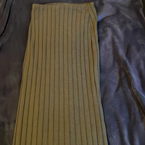 Beige ribbad långkjol - Snygg beige långkjol med ribbad design. Perfekt för en stilren look. Kjolen har en enkel och elegant passform som passar till många olika tillfällen.