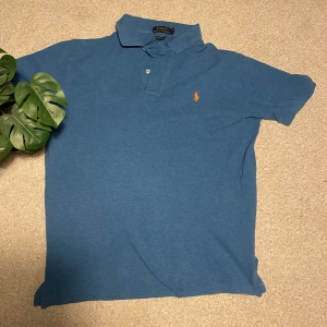 Blå pikétröja från Ralph Lauren - Säljer en klassisk blå pikétröja från Ralph Lauren. Den är perfekt för dom varmare dagarna nu till våren. Perfekt för en avslappnad men stilfull look. 🌟 Priset kan gå ner 