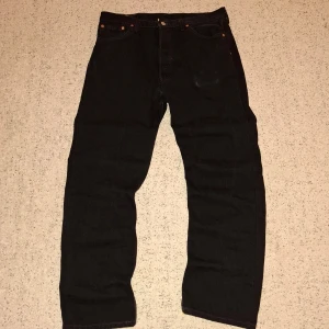 Svarta Levis 501 jeans - Säljer ett par klassiska svarta Levis 501 jeans. De har en rak passform och knappar i gylfen. Perfekta för en stilren look. Märkeslappen sitter på baksidan av midjan. Pris kan diskuteras!