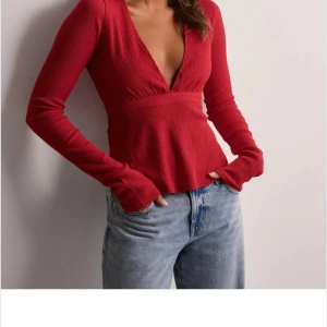 Röd ribbad topp från Nelly - Säljer en snygg röd ribbad topp från Nelly med v-ringning och knytband i midjan.                            Använd 1 gång  