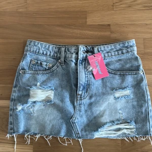 Jeanskjol blå - Trendig jeanskjol från Edikted i blå denim med slitna detaljer och fransig nederkant. Aldrig andvänd med lappen kvar