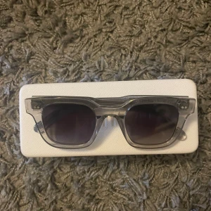 Chimi 04 grey  - Snygga grå solglasögon från Chimi med transparent båge och mörka linser. Perfekta för en stilren look. Kommer med ett praktiskt fodral för säker förvaring. Skriv gärna om ni har några frågor 