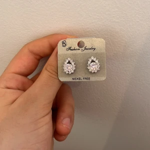 Glittriga örhängen från Fashion Jewelry - Nickelfria örhängen med glittrande stenar i en elegant design. Perfekta för att ge en extra touch av glamour till din outfit. De har en klassisk stil som passar till många tillfällen.