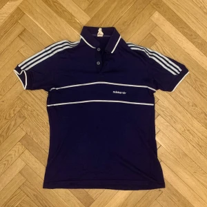 Vintage mörkblå pikétröja Adidas - Vintage mörkblå/ marinblå pikétröja från adidas. Små hål som enkelt kan lagas om man bryr sig :) 