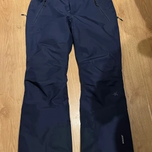 Blå skidbyxor från Everest 36 - Säljer ett par blå skidbyxor från Everest med Recco-teknologi. Byxorna har dragkedjor vid fickorna och justerbara remmar i midjan för bästa passform. Perfekta för vinterns äventyr i backen! ( köpt hängslen till dom ifall man vill ha ) nypris runt 1000kr