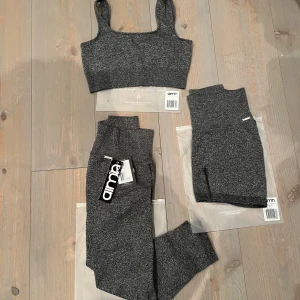 Grå ribbad träningstopp och leggings från Aim'n - Grey melange ribbed set från AIM’N. Oanvänt, skickas i förpackning. Tights: XS Shorts XS Top  S                                                                         Setet är i ett mjukt och stretchigt material som ger en bekväm passform.