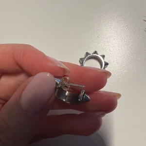 Edblad örhängen  - Coola silvriga örhängen med spetsiga nitar runt om. Perfekta för att ge en edgy touch till din stil. De är i en rund form och har en säker låsning.