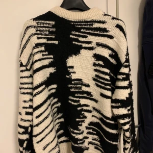Svartvit stickad tröja från Zara - Säljer en cool svartvit stickad tröja från Zara med ett abstrakt mönster. Tröjan har långa ärmar och en rund halsringning. Perfekt för att hålla sig varm och stilren under kyligare dagar.  PRIS KAN DISKUTERAS 