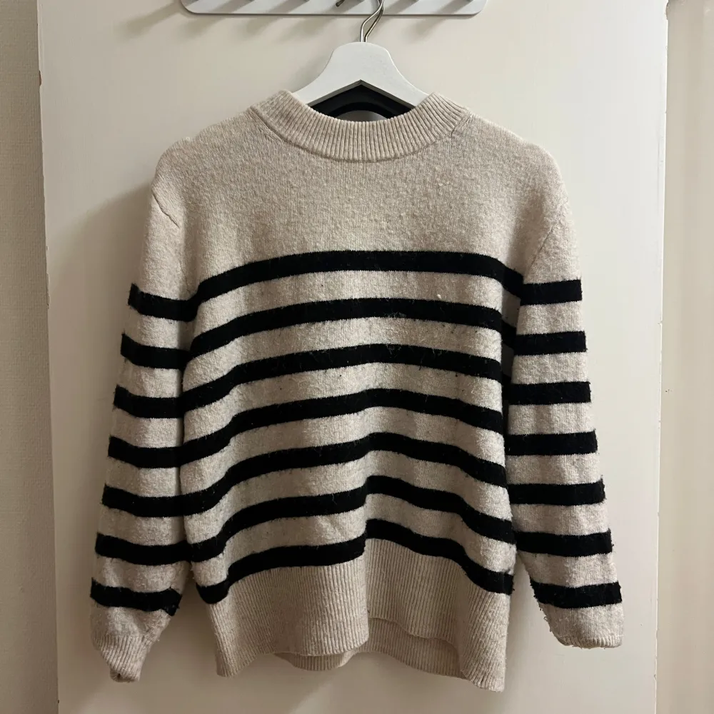Säljer en mysig randig tröja från H&M i beige och svart. Tröjan har långa ärmar och en ribbad krage samt nederkant. Perfekt för en avslappnad stil.. Neuletakit & Villapaidat.