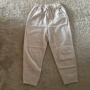 Beige byxor från Stradivarius - Säljer ett par beige byxor från Stradivarius med elastisk midja och knappstängning. Byxorna har en avslappnad passform och super sköna, använd få gånger bara. ☺️✨