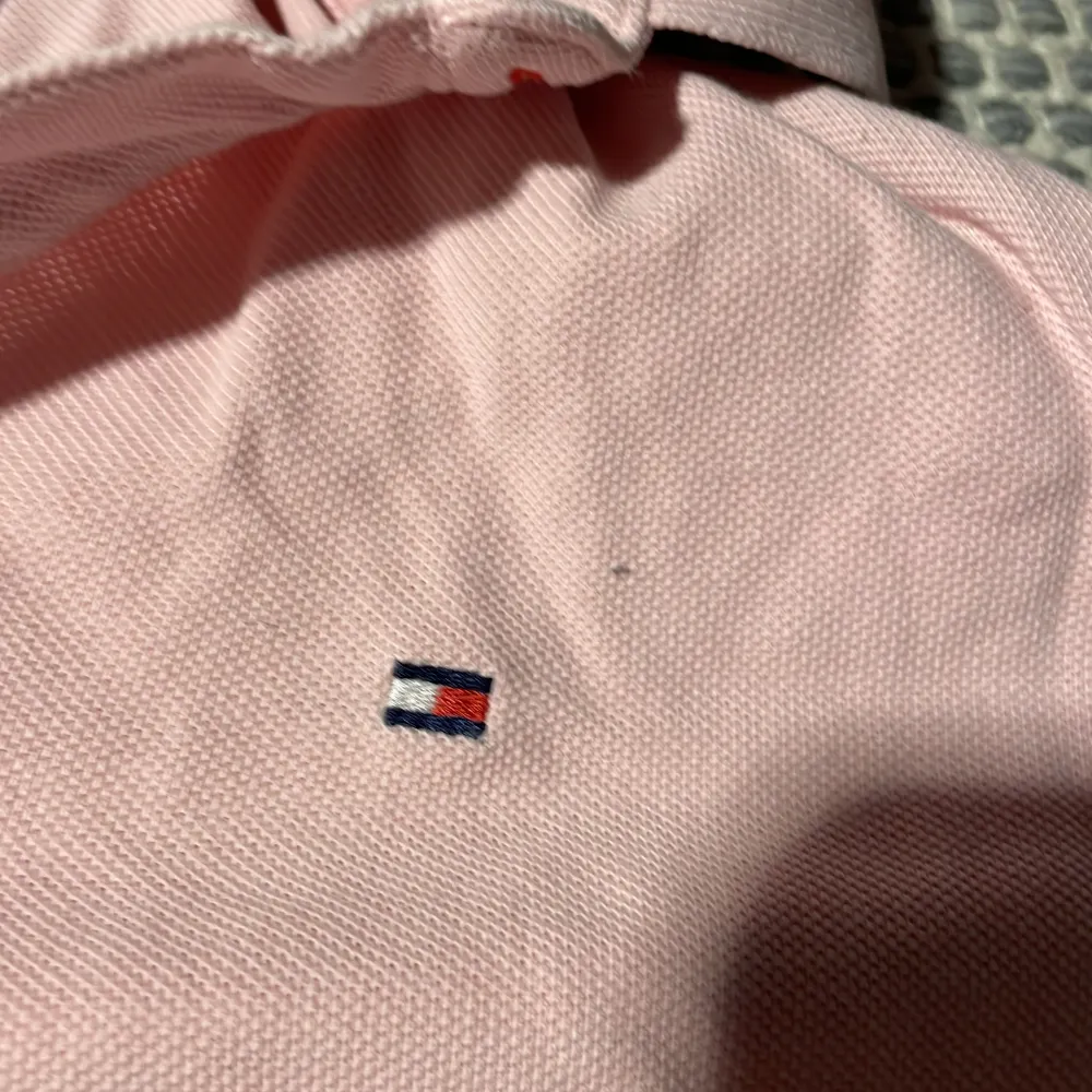 Säljer en stilren rosa pikétröja från Tommy Hilfiger. Tröjan har korta ärmar och en klassisk krage. Perfekt för en avslappnad och snygg look. 💖. Neuletakit & Villapaidat.