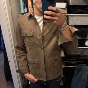Beige overshirt från Tiger of Sweden - Säljer en stilren beige/brunn overshirt från Tiger of Sweden.  Helt i nyskick, knappt använd, Perfekt för lager på lager. Jag på bilden är 186cm