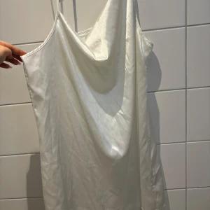 Vit klänning från Shein - Säljer en stilren vit klänning från Shein med tunna axelband och en elegant drapering framtill. Perfekt för en minimalistisk look.