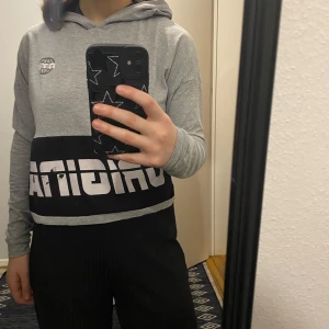 Grå hoodie från Adidas - Säljer en grå hoodie från Adidas med svart och vit logga framtill. Tröjan har en bekväm passform med långa ärmar och en huva. Perfekt för en avslappnad stil.