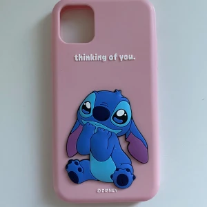 Rosa mobilskal med Stitch från Disney IPhone 11 - Sött rosa mobilskal med en bild av Stitch och texten 'thinking of you'. Perfekt för Disney-fans som vill skydda sin telefon med stil.