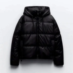 Svart pufferjacka med huva - Snygg svart pufferjacka med huva och dragkedja. Perfekt för kyliga dagar med sin vadderade design. Jackan har långa ärmar och en stilren look. Nästan aldrig använd 