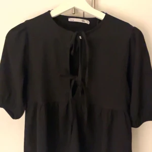 Svart blus med knytning - Snygg svart blus, med korta ärmar och knytning framtill och storlek xs från lager 157, helt oanvänd och perfekt för utekvällar eller andra aktiviteter🤍