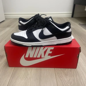 Nike Dunk Low Retro pandas - Snygga Nike Dunk Low Retro sneakers i klassisk svart och vit färgkombination. Skorna har en stilren design med snörning och en bekväm passform. Skorna är använda ett fåtal gånger och är i ett mycket bra skick. Tveka inte på att höra av dig vid minsta fundering.