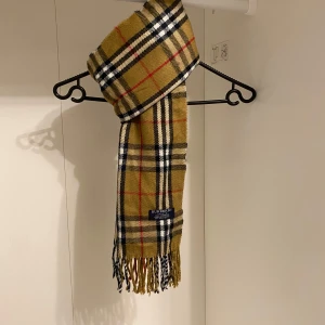 Burberry - Säljer nu denna Snygga rutig halsduk från Burberry.  Den är i färgen beige, och den är i mycket fint skick. Och den är i gjord i 100% kashmir. Perfekt för att hålla dig varm och stilren under kyliga dagar. Hör av dig vid funderingar☺️