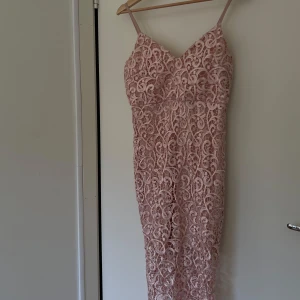 Rosa spetsklänning - Elegant rosa klänning med vacker spetsdesign och smala axelband. Perfekt för speciella tillfällen med sin feminina och stilrena look. Handgjord från Beirut, Libanon. 