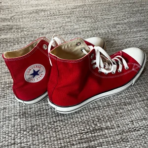 Röda Converse All Star sneakers (Nya) - Snygga röda Converse All Star sneakers i klassisk design med vita snören och tåhätta. Perfekta för en avslappnad stil med den ikoniska loggan på sidan. (Helt nya)