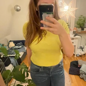 Gul ribbad topp från H&M - Säljer en gul ribbad topp från H&M Basic. Toppen har korta ärmar och en rund halsringning. Perfekt för en färgglad touch till din outfit! Står att den är L men passar även M💕