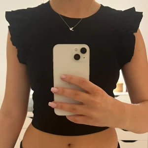 Svart topp med volangärmar från Zara - Snygg svart topp från Zara med volangdetaljer på ärmarna. Perfekt för en stilren look. Aldrig använd. Passar XXS-S