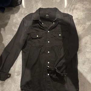 Svart skjorta från Zara - Snygg svart skjorta från Zara i relaxed fit. Skjortan har långa ärmar och knappar framtill samt två bröstfickor med knappstängning. Perfekt för en stilren look. perfekt för grich och funkar som en jacka till våren och ganska utsläppt🔥🔥