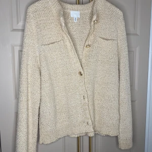 Beige stickad kofta från H&M - Mysig beige stickad kofta från H&M med knappar framtill. Perfekt för kyliga dagar med sin mjuka och bekväma passform. Koftan har långa ärmar och en klassisk rund halsringning.