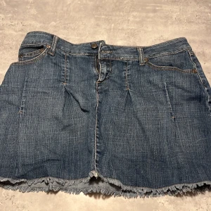 Jeanskjol från Zoul - Trendig jeanskjol från Zoul med fransig kant och broderade detaljer på bakfickorna. Kjolen har en klassisk femficksdesign och stängs med knapp och dragkedja. Perfekt för en avslappnad stil. Den är för stor för mig men enligt mig har den väldigt fina bakfickor 💗