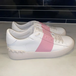 Valentino Skor  - Säljer ett par feta Valentino Skor i vitt skinn med en bred rosa rem. Perfekta för både vardag och fest!!