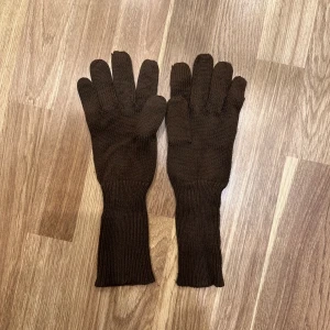  - Bruna stickade vantar. De är långa och varma, perfekta för kalla dagar. 