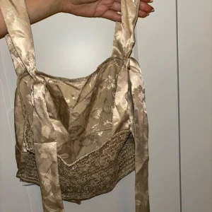 Beige korsettopp med blommönster - Säljer en superfin beige partytopp med ett subtilt blommönster. Perfekt för festliga tillfällen eller en utekväll. 