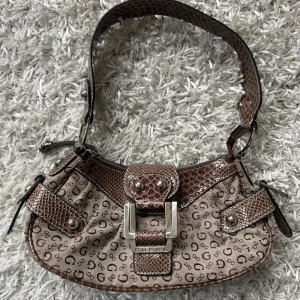 Guess handväska  - Så fin brun guess handväska som passar  till allt. Skick enligt bild. Något trög dragkedja. Köp sker via köp nu, jag postar inom 24h. Kvar tills markerad såld 