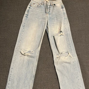 Högmidjade jeans med hål  - Säljer ett par högmidjade jeans med hål i på knäna. Storlek 32