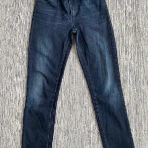 Mörkblåa jeans i strl 26/32 från Acne Studio, modell Flex Basement. - Mörkblåa jeans i strl 26/32 från Acne Studio, modell Flex Basement.  Använda men i fint begagnat skick.  Mått Midjan: ca 37 cm Längd från grenen och ner: ca 72 cm  98% bomull och 2% elastan  Kommer från ett djur och rökfritt hem.